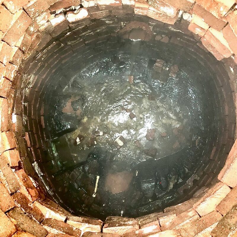 Brick manhole with missing bench and severe groundwater infiltration before rehabilitation